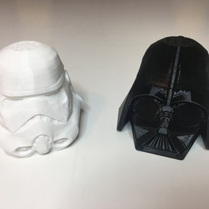 May include: A white 3D printed Star Wars Stormtrooper helmet and a black 3D printed Darth Vader helmet.