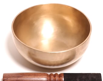 Könnte beinhalten: Eine polierte, goldfarbene Klangschale aus Metall mit glatter, abgerundeter Innen- und Außenseite. Dazu gehört ein Holzschlägel mit einem dunkelbraunen Holzgriff, einem gerippten Griffbereich und einem schwarzen, mit Filz überzogenen Ende.