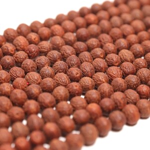 May include: A collection of round, reddish-brown beads arranged in multiple parallel rows. Each bead features a distinct, textured, and wrinkled surface pattern, creating a uniform appearance across the entire group of spherical components.