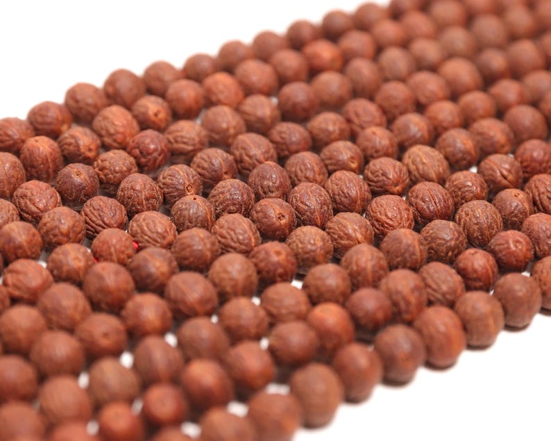 May include: A collection of round, reddish-brown beads arranged in multiple parallel rows. Each bead features a distinct, textured, and wrinkled surface pattern, creating a uniform appearance across the entire group of spherical components.