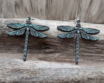 May include: A pair of teal blue dragonfly earrings made of wood with silver hooks.
