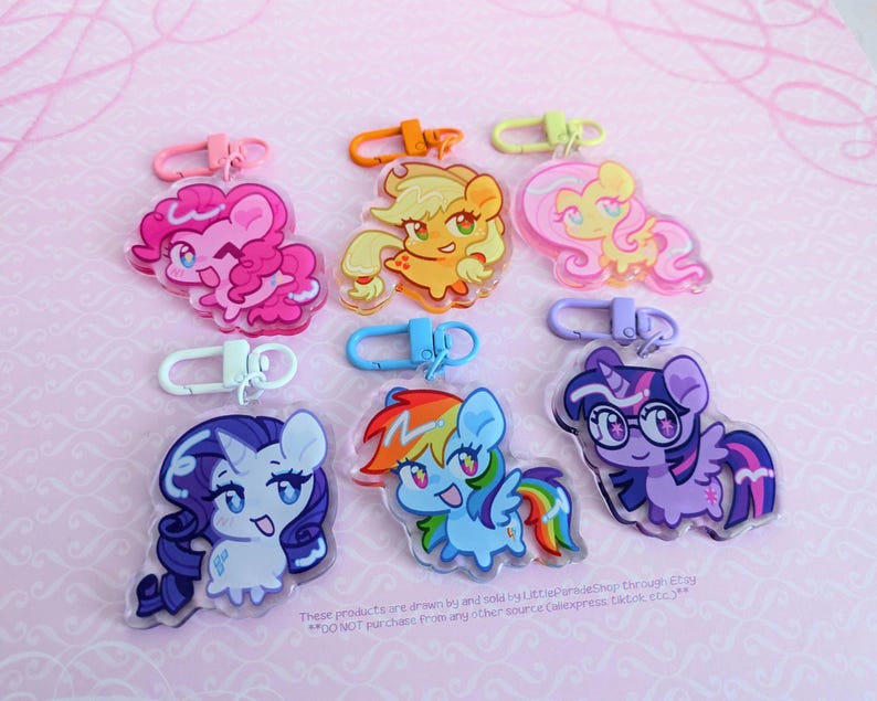 May include: Six acrylic keychains featuring cartoon pony characters with colorful manes and tails. Each charm is attached to a plastic lobster clasp in a matching color, including pink, orange, yellow, white, blue, and purple hardware.