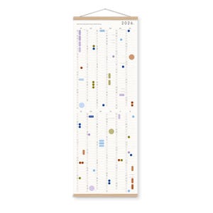 K&ouml;nnte beinhalten: Ein vertikaler Wandkalender f&uuml;r 2026 mit einem hellen Holzrahmen oben und unten sowie einer Aufh&auml;ngeschnur. Das wei&szlig;e Papier zeigt ein Raster aus Monaten und Tagen, das mit verschiedenen farbigen Kreisen und ovalen Symbolen in Blau, Gr&uuml;n und Braun markiert ist.