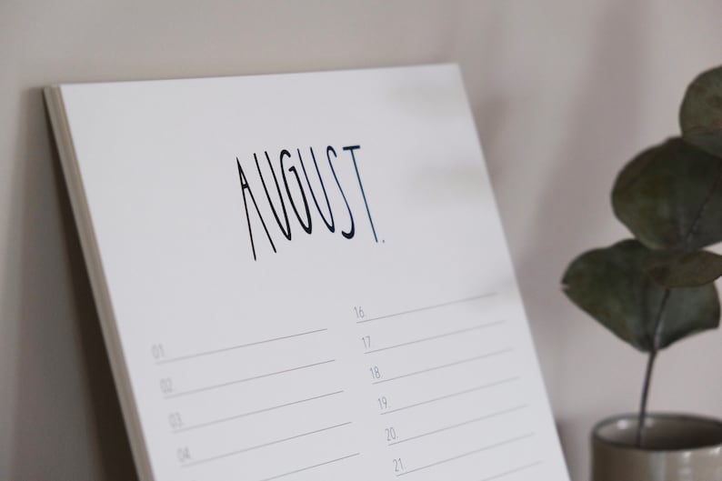 May include: A white calendar with the word "AUGUST" written in black ink. The calendar has lines for each day of the month, starting with the 16th.
