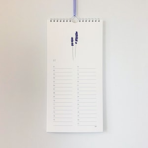 Pu&ograve; includere: Un calendario bianco con un'illustrazione di un fiore di lavanda. Il calendario &egrave; per luglio e ha i numeri da 1 a 31 elencati.