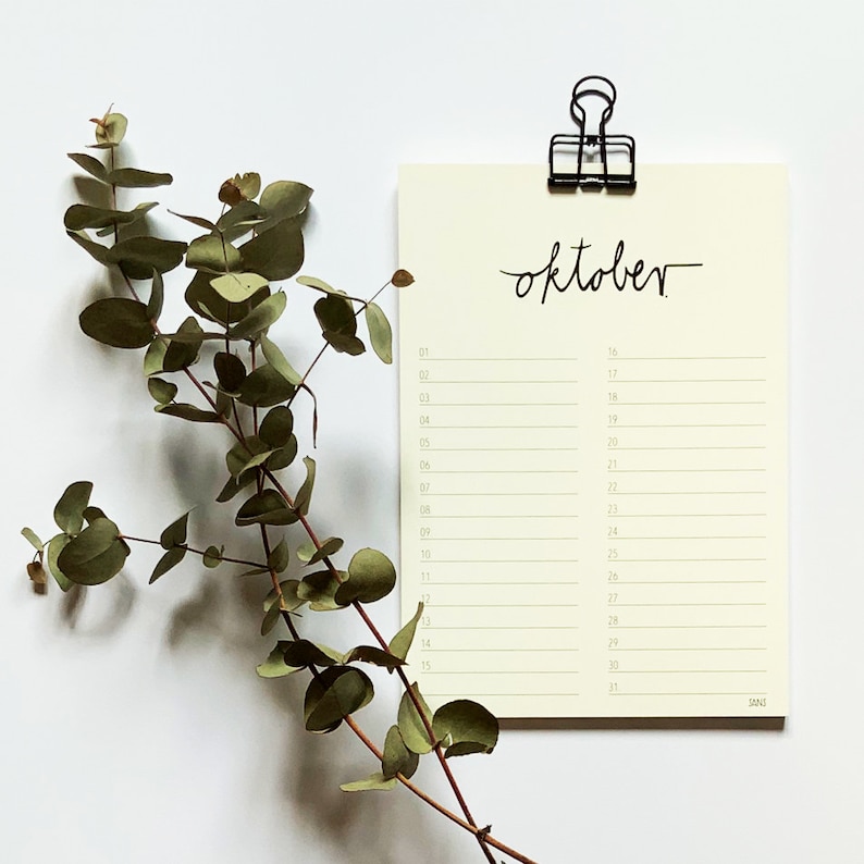 May include: A simple, blank calendar for the month of October. The calendar is printed on cream-coloured paper and has a black clip at the top.
