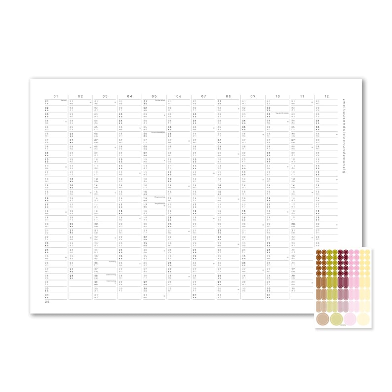 Peut inclure: Un calendrier mural blanc avec une grille pour douze mois, pr&eacute;sentant du texte et des chiffres noirs. Le texte "zweitausendiebenundzwanzig" est imprim&eacute; verticalement sur le c&ocirc;t&eacute; droit. Une feuille s&eacute;par&eacute;e de petits autocollants circulaires multicolores est incluse.