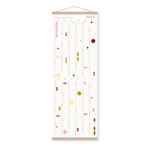 K&ouml;nnte beinhalten: Ein vertikaler Wandkalender f&uuml;r 2027 mit einem hellen Holzrahmen oben und unten sowie einer Aufh&auml;ngeschnur. Das wei&szlig;e Papier zeigt zw&ouml;lf Monatsspalten von 01 bis 12, die mit verschiedenen farbigen Kreisen und Formen in Pink, Gelb, Oliv und Dunkelrot versehen sind.