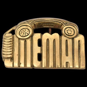 May include: A vintage brass belt buckle featuring a telephone handset design above the word "LINEMAN" in bold capital letters. The buckle has a rectangular shape with vertical lines and a classic, aged appearance.