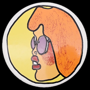 May include: A round, white ceramic plate featuring a stylized illustration of a woman's profile. The woman has orange hair, purple sunglasses, and red lips. The background is yellow, and the plate has a black outline.