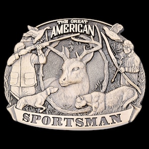 May include: A silver-toned belt buckle with a hunting theme. The buckle features a deer, hunter with a rifle, hunter with a bow, dog, and bear. The words "THE GREAT AMERICAN SPORTSMAN" are displayed on the buckle.