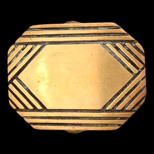 May include: A vintage brass belt buckle with an Art Deco design. The rectangular buckle features a central geometric shape and is surrounded by parallel lines and angled accents. The brass has a warm, golden hue with dark accents.