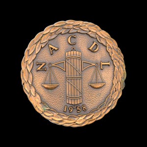 May include: A bronze circular medal with a laurel wreath border. The center features a scale with a column in the middle. The text "ACDL" is above the scale and "1958" is below.