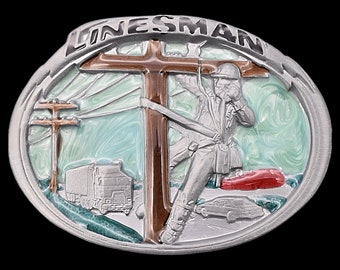 May include: Oval-shaped silver-tone belt buckle with a detailed relief design. The buckle features a lineman working on a power line, with a truck and cars in the background. The word "LINEMAN" is at the top.