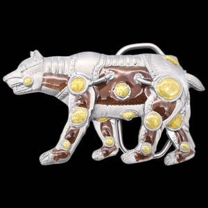 May include: A silver and brown metal belt buckle with a detailed design of a bear with yellow accents. The bear is stylized to look like a robot or machine.