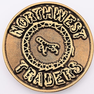 May include: A gold-colored metal token with the words "Northwest Traders" embossed around the edge. A stylized bird's foot is in the center of the token.