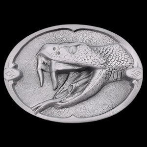 May include: A silver belt buckle with a detailed, three-dimensional design of a snake's head with fangs.
