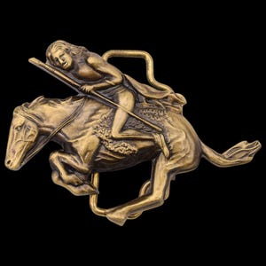 May include: A bronze-colored metal belt buckle featuring a rider on a galloping horse. The rider is holding a spear, and the buckle has a rectangular loop for the belt. The design is detailed and set against a black background.