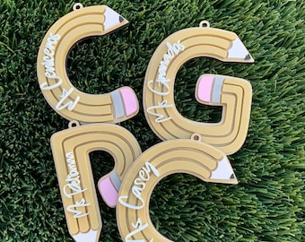 May include: Four wooden pencil-shaped ornaments with the names "Mrs. Cencea", "Mrs. Granados", "Mrs. Peterson", and "Mrs. Casey" written on them.
