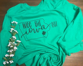 May include: A green long-sleeved t-shirt with a black graphic of the state of Iowa and the text "Wee Bit Iowa-ish".