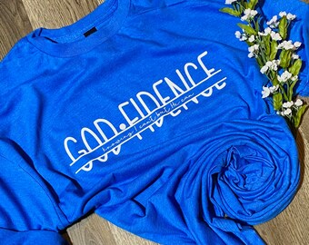May include: A royal blue t-shirt with the text "God Fidence" in white. The text is underlined and the words "knowing I can't but He can" are written in smaller font below the underlined text.