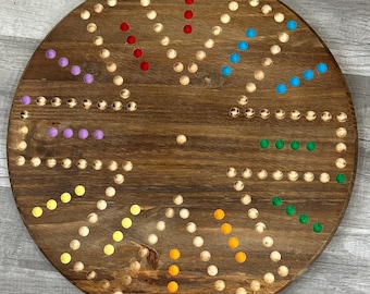 May include: A wooden game board with a circular shape and a variety of colored pegs. The board has a brown wood grain finish and features a variety of patterns and shapes. The pegs are arranged in a circular pattern around the board.