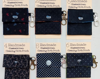 May include: Six small fabric pouches for cleaning glasses or screens, each attached to a numbered display card labeled Handmade Glasses/screen Cleaning Cloth Pouch. The pouches feature various dark patterns, snap closures, and metal swivel clasps.