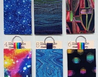 May include: Six rectangular fabric pouches with metal key rings, each attached to a cardboard tag labeled Handmade Glasses Screen. The pouches feature various patterns including blue stars, dotted gradients, geometric shapes, colorful nebula, blue swirls, and rainbow circles.