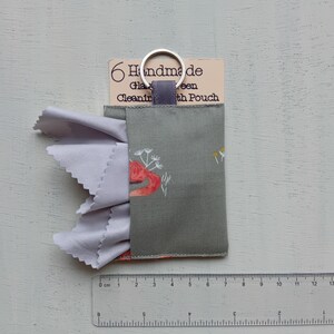 May include: A gray fabric pouch with a red fox and white floral print, featuring a silver metal keyring and a light gray microfiber cloth extending from the side. A tag reads 6 Handmade Glasses Cleaning Cloth Pouch. A ruler shows a width of 7 cm.