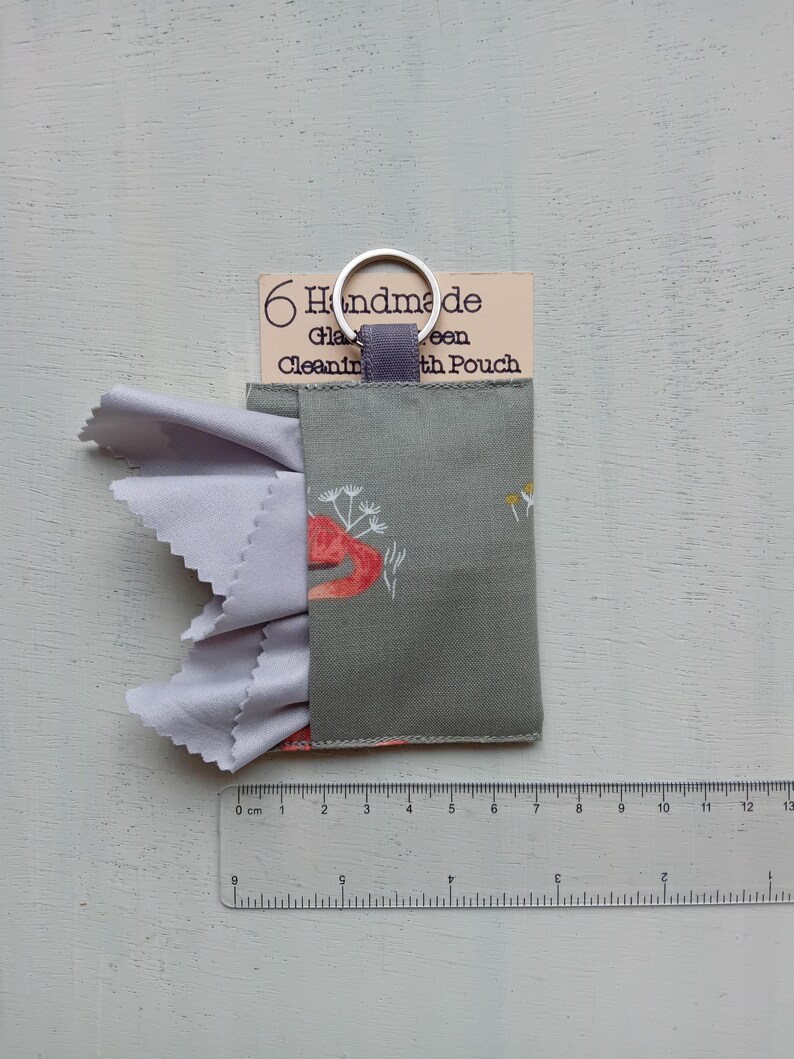 May include: A gray fabric pouch with a red fox and white floral print, featuring a silver metal keyring and a light gray microfiber cloth extending from the side. A tag reads 6 Handmade Glasses Cleaning Cloth Pouch. A ruler shows a width of 7 cm.