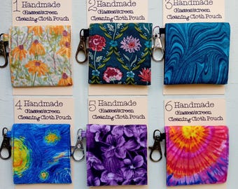 May include: Six square fabric pouches labeled Handmade Glasses/screen Cleaning Cloth Pouch, each with a metal lobster clasp. Designs include orange flowers, dark floral, blue marble, starry night print, purple flowers, and a pink tie-dye pattern.