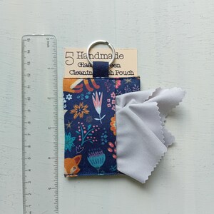 May include: A navy blue fabric pouch with a colorful floral and fox pattern, featuring a silver keyring and a light gray cleaning cloth. A clear plastic ruler shows the pouch is approximately 3.5 inches wide and 3.5 inches tall.