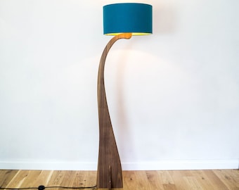 May include: A modern floor lamp with a curved wooden base and a teal fabric lampshade.