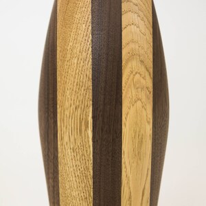 May include: A wooden vase with a striped pattern in shades of brown and light brown.