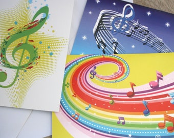 May include: Three greeting cards with musical notes and treble clefs. The first card has a green treble clef on a white background with yellow and green dots. The second card has a blue treble clef on a blue background with white stars. The third card has a rainbow background with musical notes.