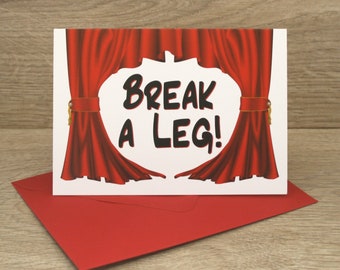 May include: A white card with red curtains pulled back to reveal the text "Break a Leg!" in black. The card is sitting on a red envelope.