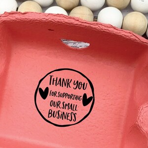May include: A red egg carton with six blue eggs inside. The carton has a black stamp that reads 