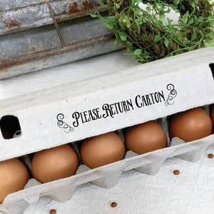 May include: A brown cardboard egg carton with six brown eggs inside. The carton has a white label that reads 