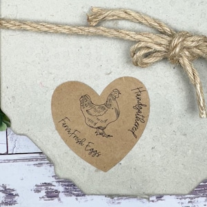 May include: A brown heart-shaped sticker with a drawing of a chicken and the text 