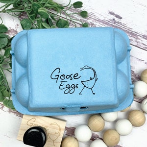May include: A blue cardboard egg carton with the words 