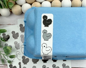 May include: A blue egg carton with a sticker of a black and white chicken on it. There are also several sheets of stickers with black and white chickens on them.