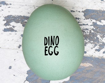 May include: A large, light green egg with the words "DINO EGG" written in black on the surface.