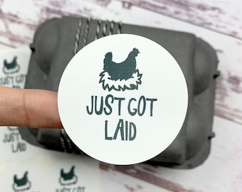 May include: A set of six white round stickers with a black silhouette of a hen in a nest and the text "Just Got Laid".