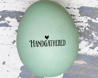 May include: A light green Easter egg with a black silhouette of a chicken and the text "HANDGATHERED" on it.