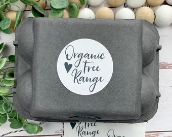 May include: A sheet of white sticker labels with black text that reads "Organic Free Range" and a small black heart. The stickers are in a circle shape and are on a gray egg carton.