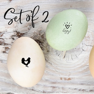 May include: Two decorated eggs, one is light green with a black heart and the words 