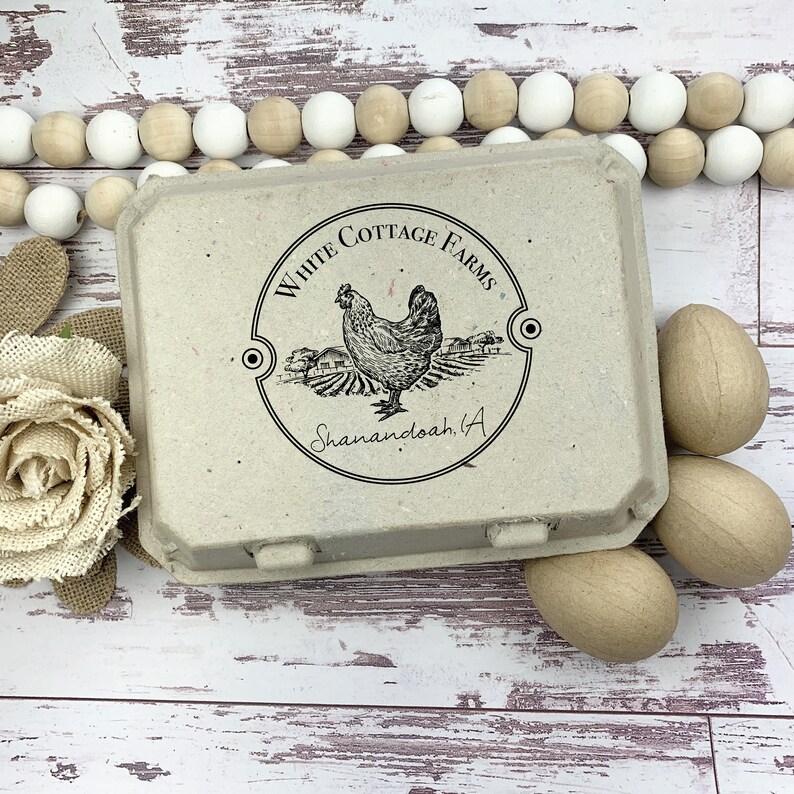May include: A beige egg carton with the text "White Cottage Farms" and a hen illustration. Three wooden eggs are next to the carton. A string of white and beige wooden beads is in the background.
