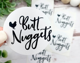 May include: White round stickers with black text that reads "Butt Nuggets" and a small black silhouette of a chicken.