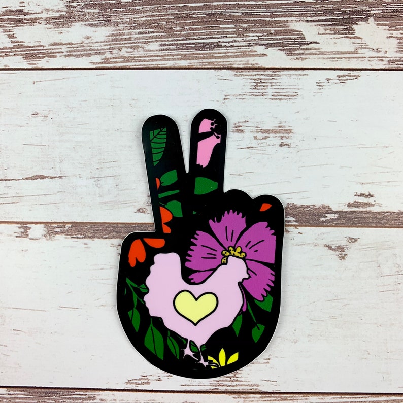 May include: A black peace sign sticker with a pink and purple flower and a pink chicken with a yellow heart in the centre. The sticker has a green, black, and red floral design.