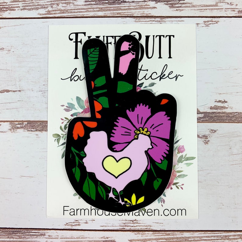 May include: Peace sign sticker with a floral design in shades of pink, green, red, and yellow. A pink chicken with a yellow heart is in the centre of the design. The sticker says "Fluff Butt Sticker" at the top and "Farmhousemaven.com" at the bottom.
